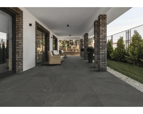 Terrasse couverte avec carrelage de sol foncé et piliers en briques.