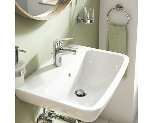 Lavabo avec robinet, miroir et accessoires de salle de bains dans une salle de bains.