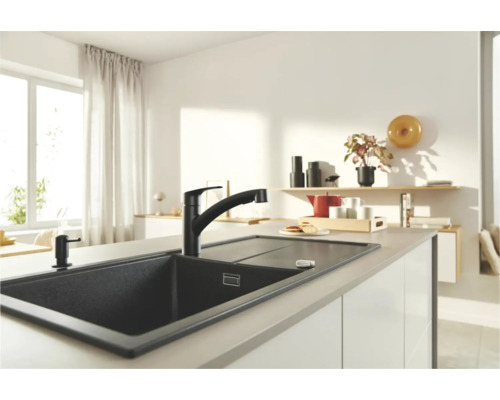Scène de cuisine avec évier foncé, robinet et distributeur de savon sur un îlot de cuisine