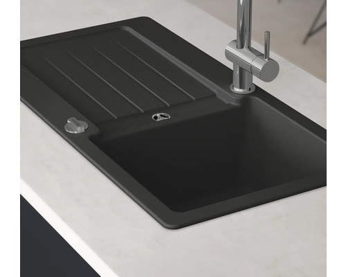 Schwarzes Spülbecken mit Abtropffläche und Wasserhahn auf einer Arbeitsplatte