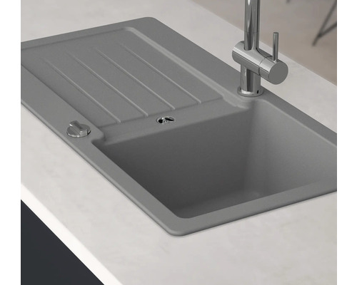 Graue Spüle mit Abtropffläche und Armatur auf einer Küchentheke.