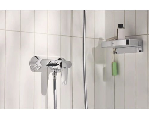 Duscharmatur und Ablage im Badezimmer mit weißen Fliesen.