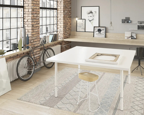 Pièce lumineuse avec grande fenêtre, table d''atelier, tabouret et décorations.