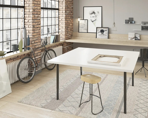 Atelier avec table blanche, tabouret et vélo devant une fenêtre