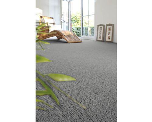 Wohnzimmer mit grauer Auslegeware, Rattanliege und geöffneter Tür