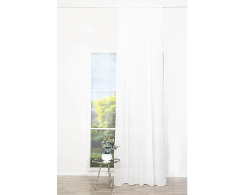 Helles Zimmer mit Fenster, weißem Vorhang und einem Beistelltisch mit Dekoration.