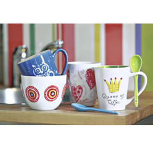 Verschiedene Kaffeebecher mit Motiven auf einer Küchentheke.