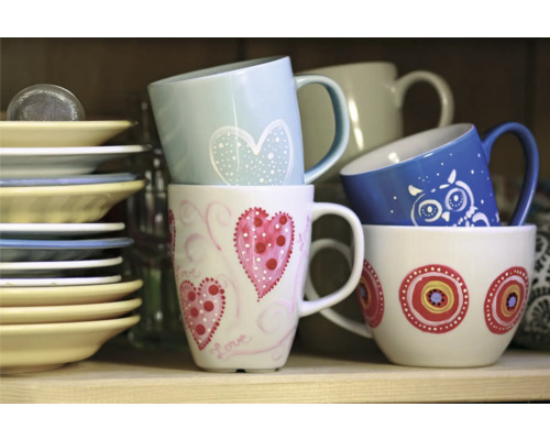 Stapel von Keramiktassen mit verschiedenen Dekoren und Tellern im Regal.