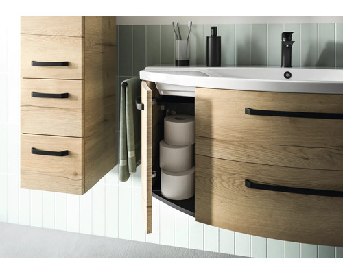 Salle de bains avec meuble sous-lavabo et armoire haute imitation bois, avec compartiment ouvert et rouleaux de papier toilette