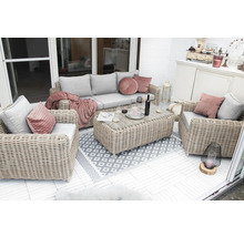 Terrasse mit Rattansitzgruppe, bestehend aus Sofa, Sessel und Tisch, dekoriert mit Kissen und Teppich