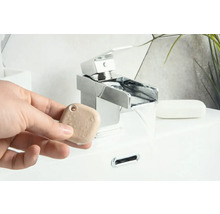 Eine Person hält einen Aromastein vor einem Wasserhahn im Badezimmer