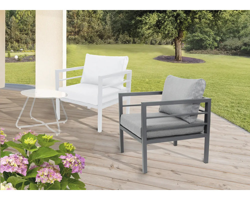 Scène de jardin avec un fauteuil lounge blanc et gris et une table d''appoint sur une terrasse