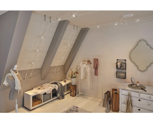 Dachzimmer mit variabel einstellbarem Schienensystem zur Deckenbeleuchtung und heller Möblierung