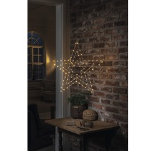 Dekorativer Stern mit LED Beleuchtung, hängend an einer Backsteinmauer über einem kleinen Tisch mit Dekoration.