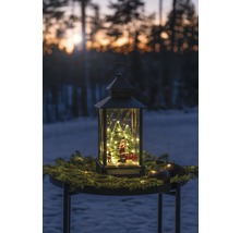 Lanterne décorative avec Père Noël, sapins et éclairage sur une table