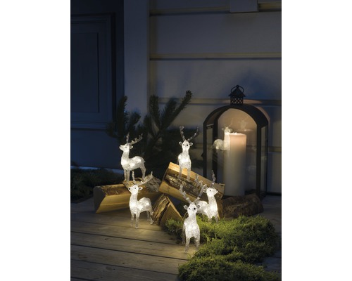 Scène décorative avec figurines de rennes illuminées, bûches de bois et une lanterne