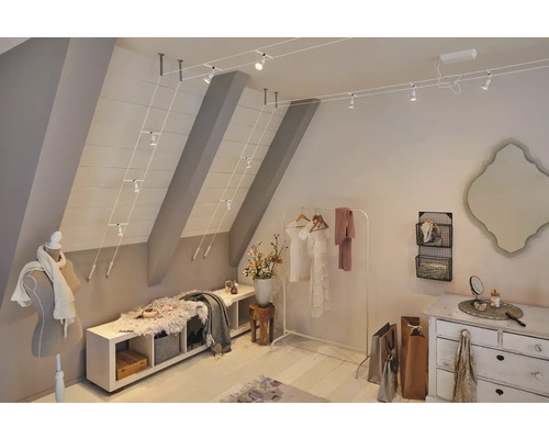 Grenier éclairé avec meubles, vêtements et objets de décoration.