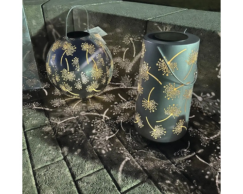 Zwei Solarleuchten aus Metall mit Löwenzahn-Muster auf Pflastersteinen.