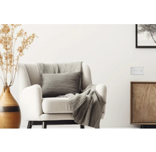Wohnzimmer mit Sessel, Kissen, Decke, Vase und Schalter