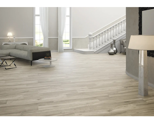 Espace de vie lumineux avec canapé, escalier et carrelage imitation bois