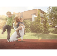 Mutter mit Kindern auf dem Spielplatz mit Fallschutzmatten vor Haus und Garten