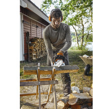 Homme coupant du bois avec une tronçonneuse sur un chevalet à bois à l''extérieur