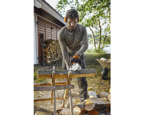 Homme coupant du bois avec une tronçonneuse sur un chevalet à bois à l''extérieur