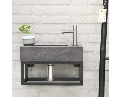 Waschtisch mit Armatur, Pflanze und Handtuchhalter vor einer Backsteinwand