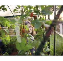 Une jeune fille dans une serre, entourée de plantes