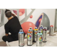 Plusieurs bombes de peinture Montana devant un mur avec un homme qui s''éloigne.