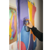 Une personne utilise de la peinture aérosol sur une toile pour des projets artistiques.