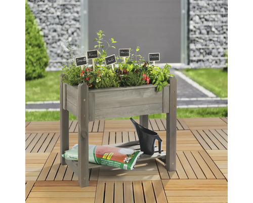 Jardinière sur pieds en bois avec herbes aromatiques et légumes, arrosoir et sac de terreau