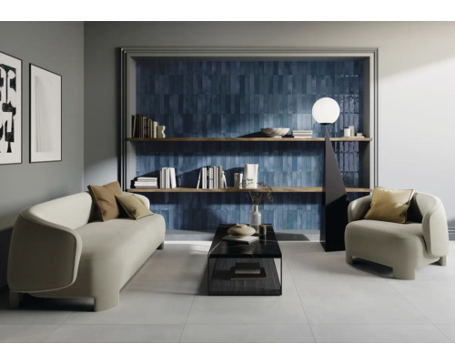 Salon avec canapé, fauteuil, table basse, bibliothèque et carreaux muraux bleus