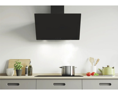 Scène de cuisine avec hotte au-dessus de la plaque de cuisson et ustensiles de cuisine sur le plan de travail.