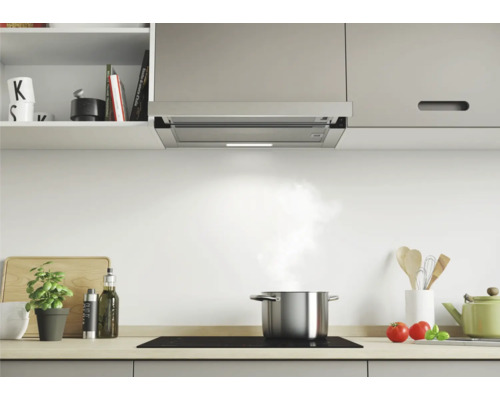 Hotte aspirante en acier inoxydable au-dessus d''une plaque de cuisson dans une cuisine lumineuse.