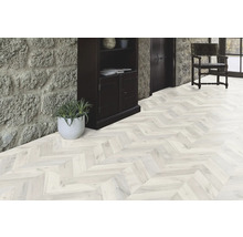 Pièce lumineuse avec parquet à chevrons, escalier en pierre et armoire en bois foncé.