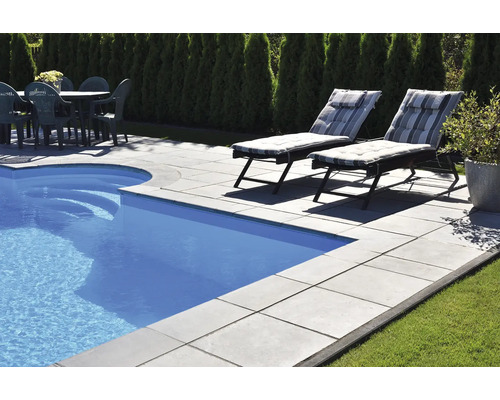 Espace piscine avec bassin, dalles en pierre, chaises longues et table de jardin avec chaises