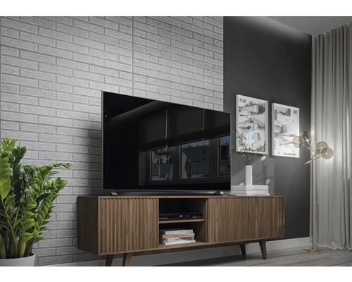 Salon avec télévision, meuble TV et mur en briques décoratif.