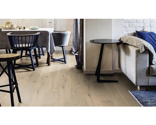 Pièce lumineuse avec parquet, chaises et table d''appoint à côté d''un canapé.