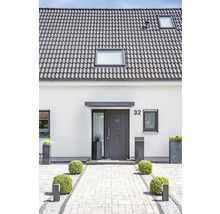 Einfamilienhaus mit grauen Dachziegeln, Haustür und gepflastertem Eingangsbereich.