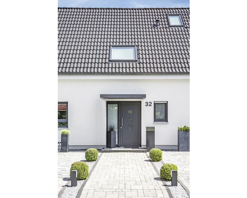 Einfamilienhaus mit grauen Dachziegeln, Haustür und gepflastertem Eingangsbereich.