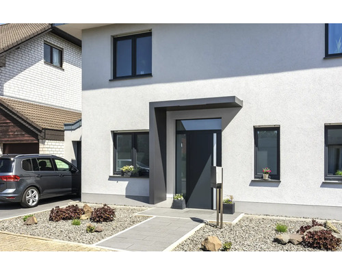 Modernes Einfamilienhaus mit Eingangsbereich, Fenstern und gepflastertem Gartenweg