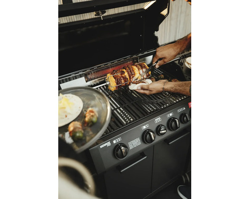 Une personne fait griller de la viande sur un barbecue à gaz Monroe Pro