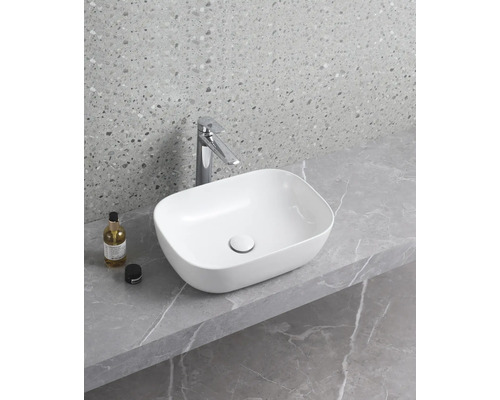 Vasque à poser en céramique avec robinetterie sur un plan de travail