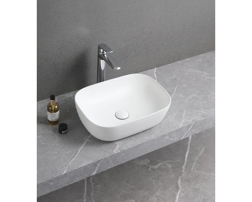 Aufsatzwaschbecken aus Keramik mit Armatur auf einer Ablage