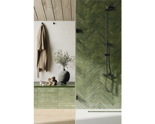 Badezimmer mit grünen Fliesen in Fischgrätenmuster, Dusche und Handtüchern
