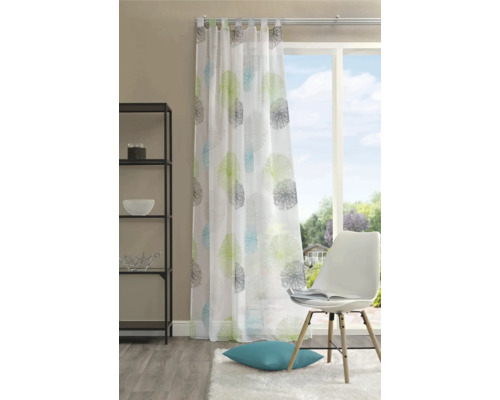 Rideau de fenêtre décoratif avec motif floral et suspension à boucles dans un espace de vie lumineux.