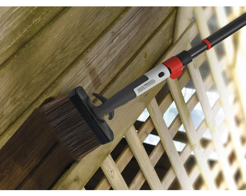Clôture en bois peinte avec une brosse plate et un manche télescopique