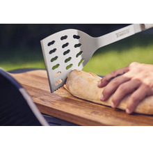 Edelstahl Grillwender schneidet Brot auf einem Holzbrett.