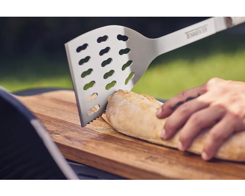 Edelstahl Grillwender schneidet Brot auf einem Holzbrett.